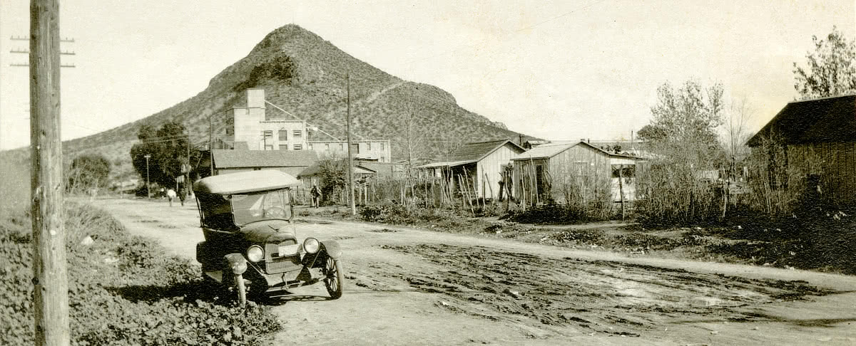 Black and white photo looking East on 1st Street towards the Hayden Flour Mill and Hayden Butte with a Model T car parked on the side of the road c. 1920.